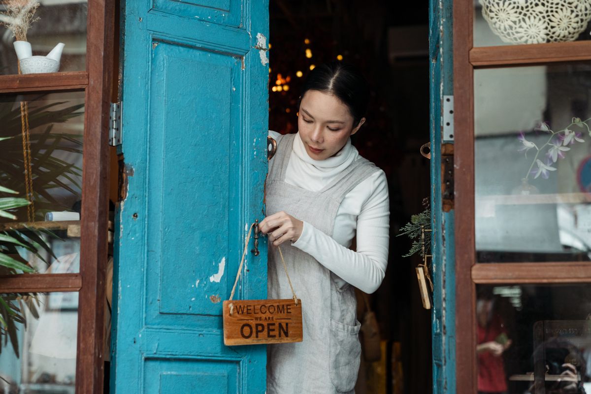 A shop owner hanging an open sign on the door